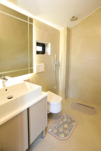 a bathroom with a sink and a toilet and a mirror at Guesthouse Micaj HORA in Himare