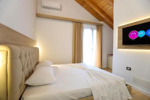 a bedroom with a white bed with a tv on the wall at Guesthouse Micaj HORA in Himare