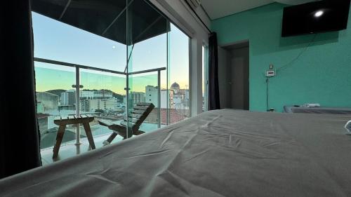 a bedroom with a bed and a view of a city at Apartamento com piscina privativa 7 minutos da basílica in Aparecida