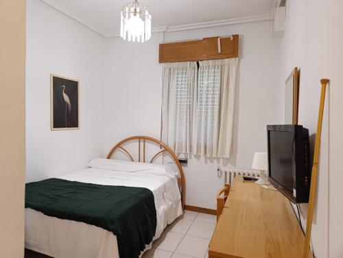 a bedroom with a bed and a flat screen tv at Hostal La Madrileña in La Gudiña