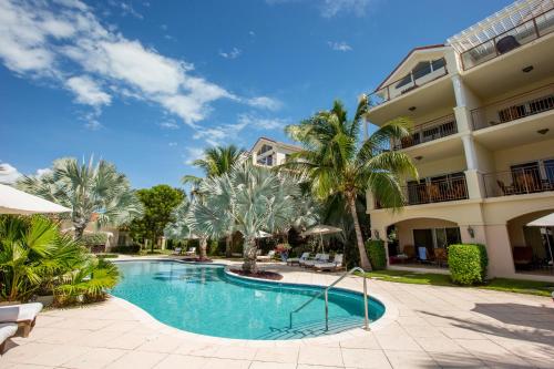 a swimming pool in front of a building with palm trees at Villa del Mar in Grace Bay