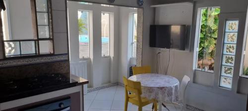 a kitchen with a table and yellow chairs in a room at Quarto Pernoite Costa do Sol in Macaé
