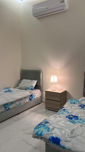 a bedroom with two beds and a lamp on a night stand at المجيدل للشقق المفروشة in Arar
