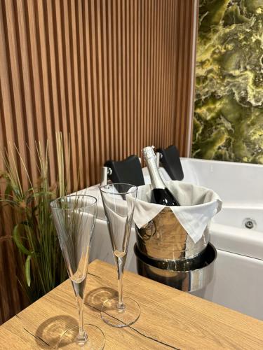 two wine glasses on a table with a basket of wine bottles at 313 Villa City Center in Tirana