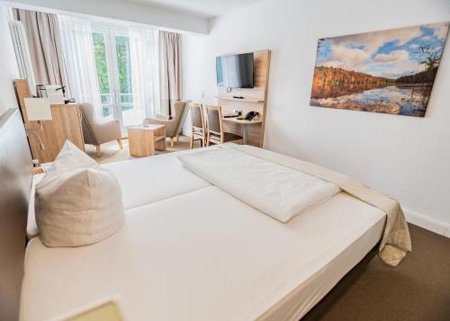 a bedroom with a large white bed in a room at Hotel Waldhalle in Mölln