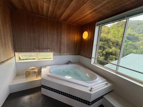 a bathroom with a tub in a room with a window at Villa Yurimun in Tatsugo