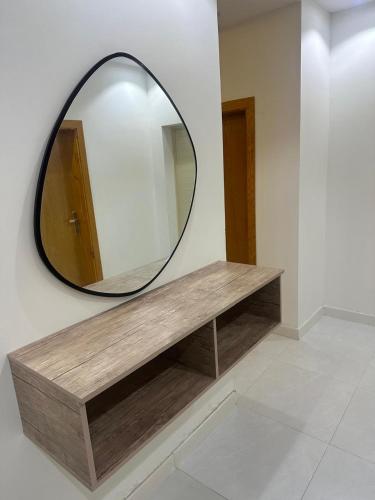 a mirror on a wall next to a wooden bench at شقة غرفتين وصالة in Musaylah