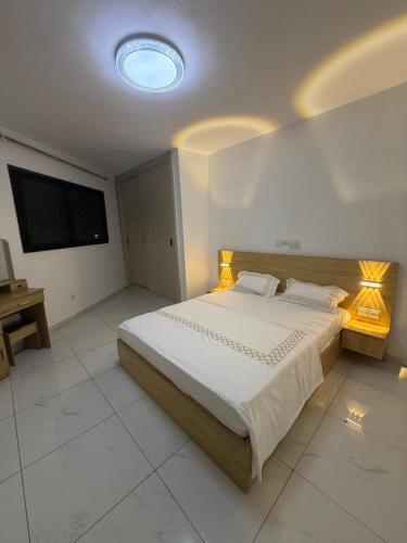 a bedroom with a large bed and a flat screen tv at Résidence sauver in Abidjan