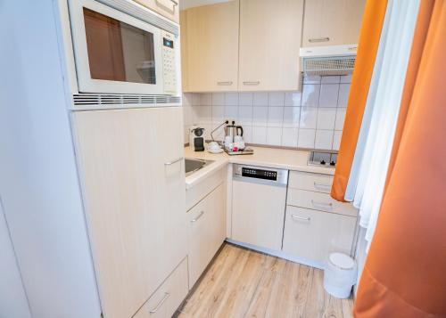 a small kitchen with white cabinets and a sink at Hotel Waldhalle in Mölln