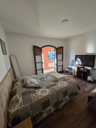 a bedroom with a bed and a flat screen tv at Chácara Minas Garten in Jundiaí
