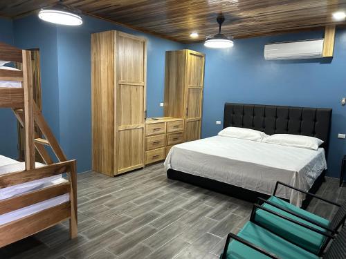 a bedroom with blue walls and a bed and bunk beds at Las Pavitas Arenal Suites in Fortuna