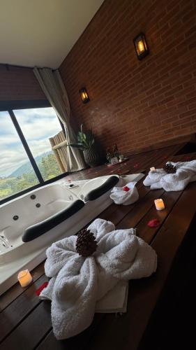 a bathroom with a tub and towels on the floor at Chalé Raízes in Joanópolis