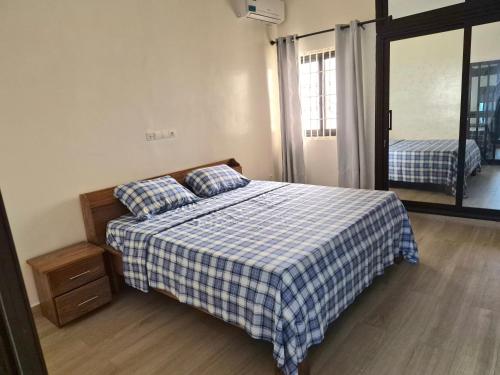 a bedroom with a bed with a blue and white checkered blanket at EmElla Manor in Komé