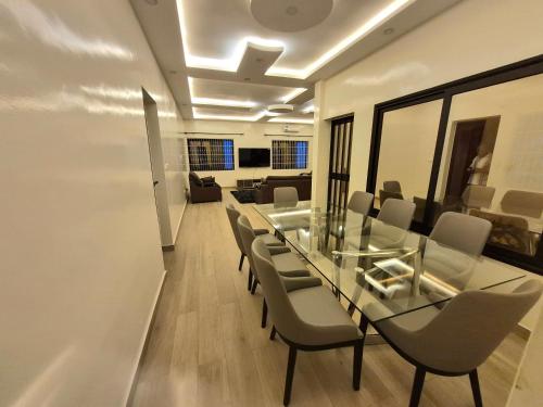 a dining room with a glass table and chairs at EmElla Manor in Komé