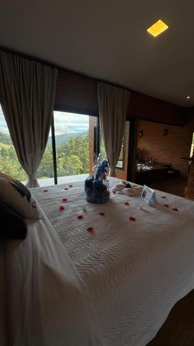 a woman sitting on a bed with roses on it at Chalé Raízes in Joanópolis