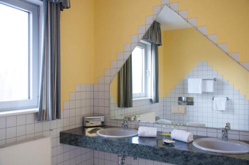 łazienka z 2 umywalkami i lustrem w obiekcie Hotel Stadt Püttlingen w mieście Püttlingen