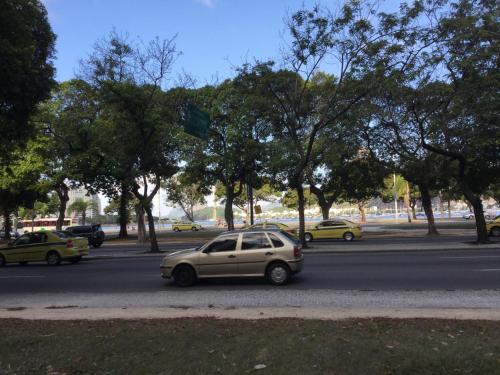a car is driving down a street with trees at Aragão Botafogo Studio in Rio de Janeiro