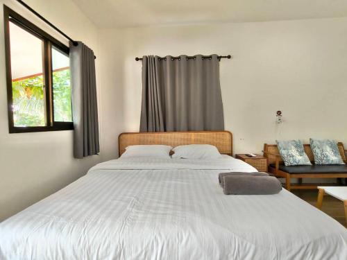 a bedroom with a large white bed with a window at First light beach bungalow in Ko Phangan