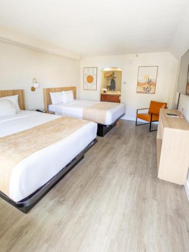 ein Hotelzimmer mit zwei Betten und einem Schreibtisch in der Unterkunft The Alcala Hotel Mission Valley Seaworld in San Diego