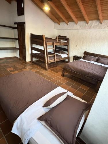 a room with two beds and a bunk bed at Hotel Lancers in Paipa