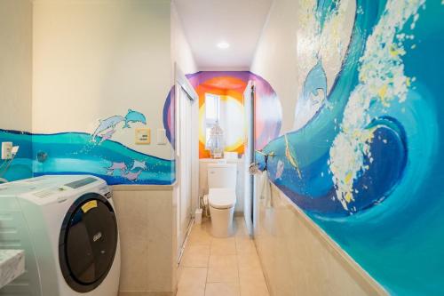 a bathroom with a wave painted on the wall at The Mural Art House Bise in Motobu