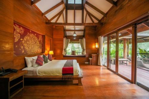 a bedroom with a bed in a room with wooden walls at Sukantara Cascade Resort and Spa in Mae Rim