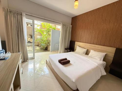 a bedroom with a large white bed and a window at Lushy Hostel Canggu in Canggu