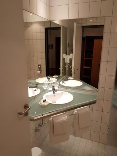 a bathroom with two sinks and a large mirror at Hotel Zur Mühle in Lengerich