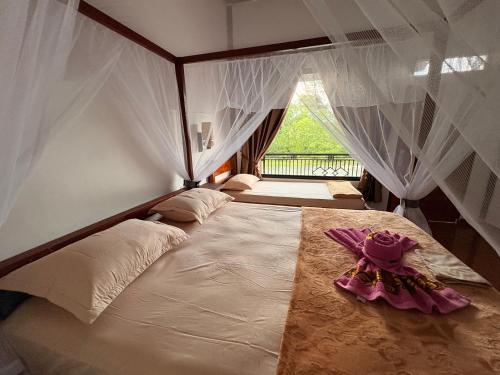 a bedroom with a large bed with a window at Asim Paris Guesthouse & jungle trekking in Bukit Lawang
