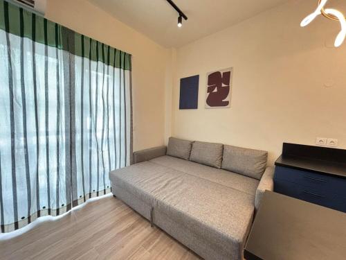 a living room with a couch and a large window at Volos Blue Nest in Volos