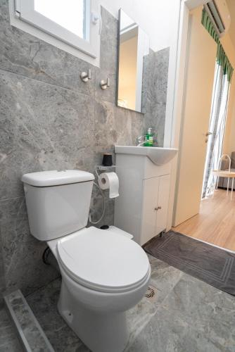 a bathroom with a white toilet and a sink at Volos Blue Nest in Volos