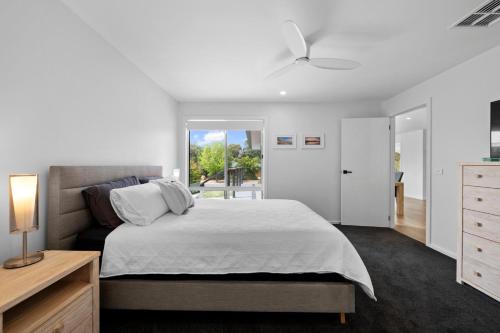 a white bedroom with a bed and a window at Links Golf Retreat in Mansfield