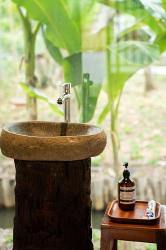 a bathroom sink sitting on top of a tree stump at Mango Home in Ben Tre