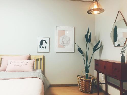 a bedroom with a bed and a dresser and a plant at 마음스테이 in Taesuha-dong