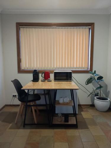 a table in a room with a window with a microwave at Baulkham Hills Deluxe King Room with Ensuite, Private Access & Air Con in Baulkham Hills