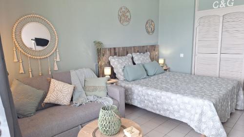 a bedroom with a bed and a couch and a mirror at Pause tropicale in Le Diamant