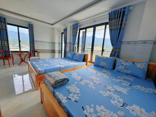 a bedroom with two beds with blue sheets and windows at Hải Phong hotel in My Luong