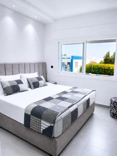 a white bedroom with a bed and two windows at Résidence Kariat Cabo 2-bedroom apartment in Cabo Negro