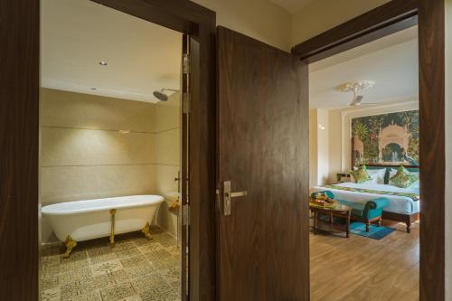 a bathroom with a tub and a bedroom with a bed at Tripli Regalia Mayur Palace in Udaipur