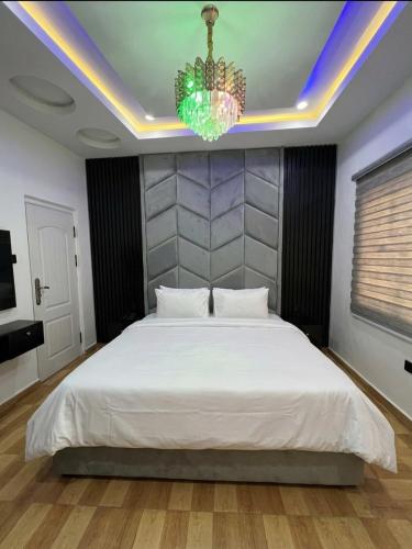 a bedroom with a large white bed with a chandelier at Hog Inn Hotel in Benin City