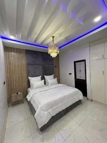 a bedroom with a large white bed with a chandelier at Hog Inn Hotel in Benin City