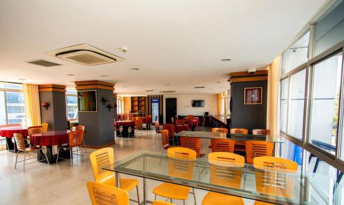 a dining room with orange chairs and a glass table at Crown Comfortia Hotel Jashore in Jessore