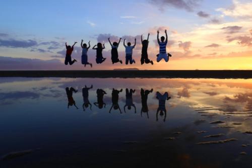 a group of people jumping in the air over a body of water at 縁-en- in Zentsuji