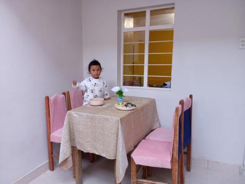 a little girl sitting at a table in a room at Abril Hostel in Mollepata