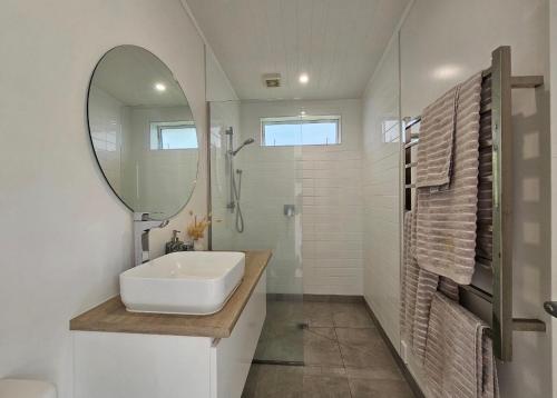 a white bathroom with a sink and a mirror at Tohora View in Waihi Beach