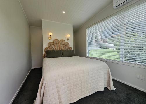 a bedroom with a bed and a large window at Tohora View in Waihi Beach