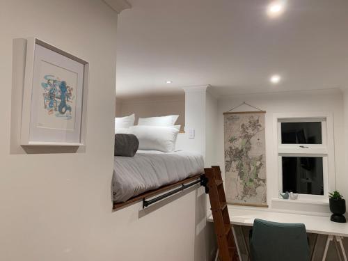 a bedroom with a bed and a desk and a window at Tiny house in the Treetops in Northland