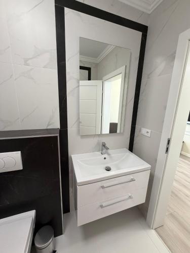 a white bathroom with a sink and a mirror at Best Luxury Residence in Bistriţa