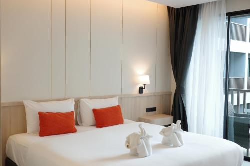 a bedroom with a white bed with orange and white pillows at Aree Tara Ao Nang Krabi in Ao Nang Beach