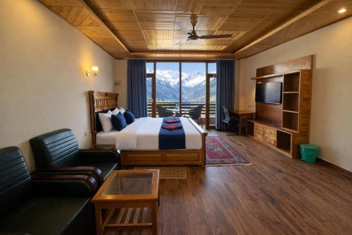 a bedroom with a bed and a couch and a television at LN Grand Premium & Luxury Suites, Manali in Manāli
